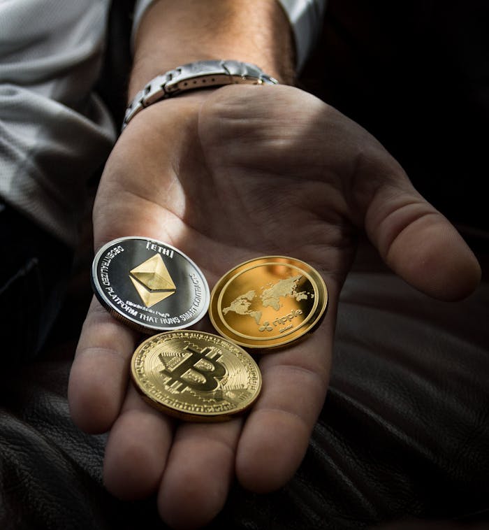 Home Hand holding Bitcoin, Ethereum, and Ripple coins representing digital currency.